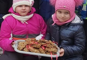 Dziewczynki trzymają tacę z gotowymi ciasteczkami dla ptaków